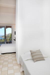 a white bedroom with a bed and a balcony at Residenza l 'Alivetu in Cargèse