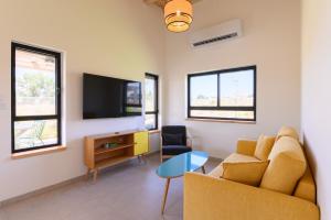 a living room with a couch and a tv at צימרים למשפחות, אירוח ~כימים אחדים~ משק אביגור-מקובר in Giv'at Yo'av