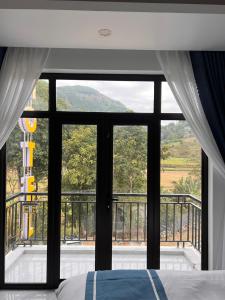 a bedroom with a large window looking out onto a balcony at New Sun Hotel in Dồng Văn