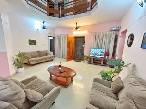 特里凡得琅La Casa Trivandrum 4 BHK AC Luxury Villa at City Centre, Just 5 kms from Airport & 3 Kms to Trivandrum Railway Station的带沙发、桌子和电视的客厅