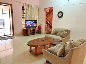 特里凡得琅La Casa Trivandrum 4 BHK AC Luxury Villa at City Centre, Just 5 kms from Airport & 3 Kms to Trivandrum Railway Station的配有桌椅和电视的客厅
