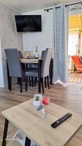 a dining room with a table with chairs and a television at Charmant mobil home camping Les Embruns in Lège-Cap-Ferret