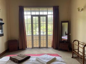a bedroom with a bed and a large sliding glass door at The Vatican in Nuwara Eliya