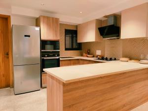 a kitchen with a stainless steel refrigerator and wooden cabinets at Luxury Suites by Eden Wellness and Hospitality in Dehradun