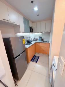 a small kitchen with a refrigerator and wooden cabinets at OPR High- floor Seaview Studio in Lapu Lapu City