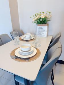 a white table with plates and glasses and a vase of flowers at OPR High- floor Seaview Studio in Lapu Lapu City +4 photos