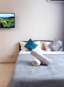 a bedroom with a bed with a tv on the wall at Уютная студия в центре города in Almaty