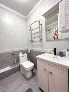 a white bathroom with a toilet and a sink at Уютная студия в центре города in Almaty +15 photos