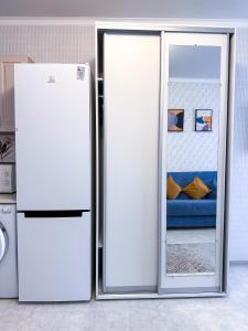 a white refrigerator in a kitchen next to a blue couch at Уютная студия в центре города in Almaty
