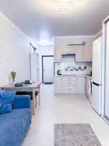 a kitchen with white cabinets and a blue couch in a room at Уютная студия в центре города in Almaty