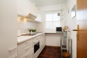 a white kitchen with a sink and a microwave at Stephan in Petersdorf auf Fehmarn