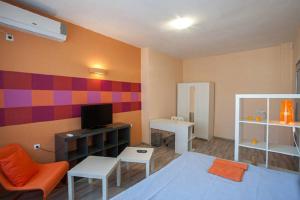 ein Wohnzimmer mit einem orangenen Stuhl und einer farbenfrohen Wand in der Unterkunft Marina Apartment in Sofia