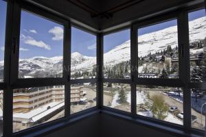 a room with windows looking out at snow covered mountains at Apartarent 1500 in Baqueira-Beret