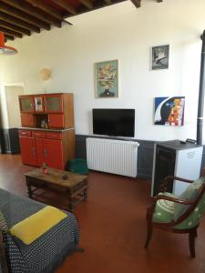 een woonkamer met een bank en een tv bij Gîte de la Ferme Feugère in Barbeville