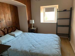 a bedroom with a bed with a blue blanket and a window at La petite maison dans le Sidobre in Fontrieu