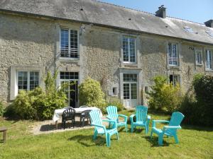 een groep stoelen en een tafel voor een gebouw bij Gîte de la Ferme Feugère in Barbeville