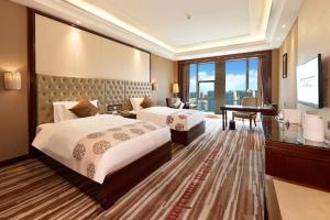 Una habitación de hotel con dos camas y un piano. en Wyndham Grand Plaza Royale Chenzhou, en Chenzhou