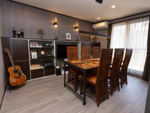 a dining room with a wooden table and a guitar at Five Roses House in Tokyo