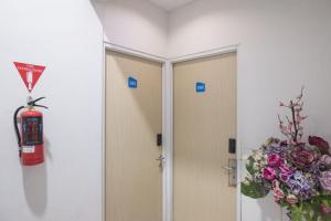 a room with a fire extinguisher next to a door with flowers at INNCA Telaga Bodas, Semarang in Jatingaleh