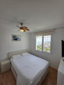 a white bedroom with a bed and a ceiling fan at Sevinc Akasya House in Milas