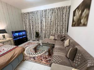 uma sala de estar com um sofá e uma TV em Luxury master room like hotel em Sabkhah