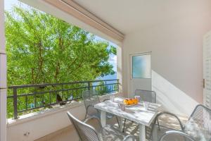 un balcone con tavolo e sedie e una grande finestra di A Minute to the Sea Brela a Brela Altre 36 foto