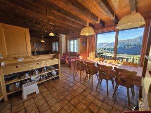 un comedor con mesa y sillas y una gran ventana en L'Epis, en Champoussin