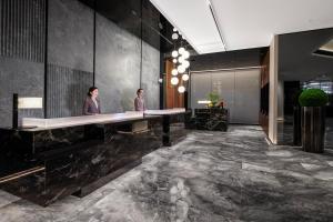 two people standing at a long desk in a lobby at Intercity Hotel Shanghai City Center - Free Mini Bar in Shanghai