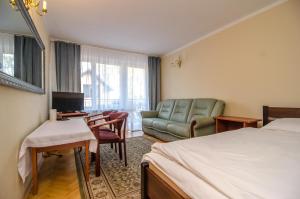 a hotel room with a bed and a couch and a chair at Willa Koron a Mielno in Mielno