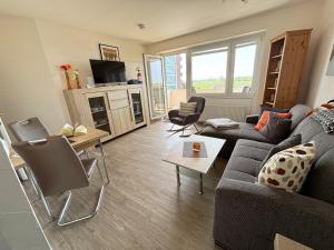 una sala de estar con un sofá y una mesa en Tief 10 Meeresbrise 402, en Wangerland
