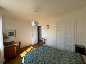 Schlafzimmer mit einem Bett, einem Schreibtisch und einer Tür in der Unterkunft Le nid d'Hirondelle in Vanault-les-Dames