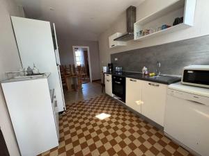 eine Küche mit weißen Schränken und einem karierten Boden in der Unterkunft Le nid d'Hirondelle in Vanault-les-Dames