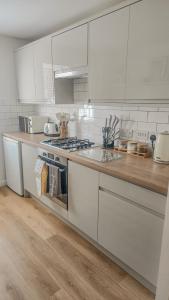 a kitchen with white cabinets and a wooden counter top at Welcome Home in Royston