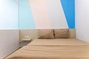 a bed in a room with a blue and white wall at INNCA Mimpi Inn, Semarang in Jatingaleh