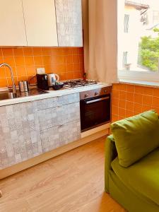a kitchen with a stove and a green couch at In centro dalla Maddy in Udine
