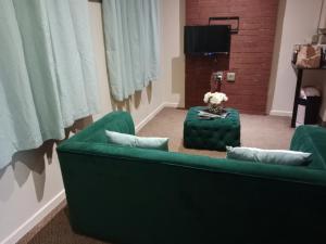 sala de estar con 2 sofás verdes y TV en City Haven 519, en Johannesburgo