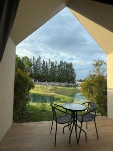 einen Tisch und Stühle auf einer Veranda mit Seeblick in der Unterkunft Sek Sky Villa&Cafe in Ban Kham Kom