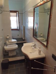 un bagno con lavandino, WC e specchio di Casa Bonifati a Cittadella del Capo Altre 9 foto