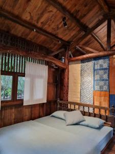 a bed in a room with wooden walls and windows at Yên homestay in Hoi An
