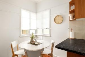 a kitchen with a white table and chairs and a clock at Smart Suites Self Check-In Cottage - Carina in Brisbane