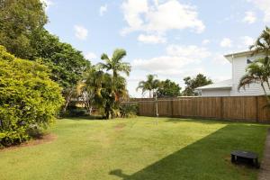a backyard with a fence and a yard with palm trees at Smart Suites Self Check-In Cottage - Carina in Brisbane +15 photos