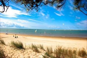 a beach with people and sailboats in the water at MobilHome climatisé 3 chambres 2 salles de bain, camping 4 étoiles, Les Charmettes in Les Mathes