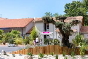 two people walking in front of a house at MobilHome climatisé 3 chambres 2 salles de bain, camping 4 étoiles, Les Charmettes in Les Mathes