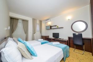 a hotel room with two beds and a mirror at Hotel Odissey Jaz in Budva