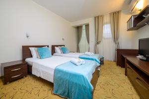 a hotel room with two beds and a flat screen tv at Hotel Odissey Jaz in Budva