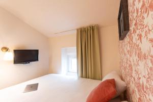 a bedroom with a bed and a tv on the wall at Résidence du Théâtre in Bordeaux +51 photos