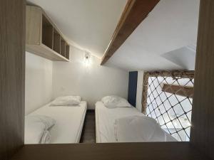two beds in a small room with a window at Superbe RDC terrasse centre ville clim wifi in Saintes-Maries-de-la-Mer