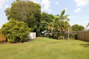 a backyard with a fence and a yard with trees at Smart Suites Self Check-In Cottage - Carina in Brisbane