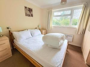 een slaapkamer met een wit bed met een raam bij Dog Friendly Chalet At Broadland Park And Marina In Lowestoft Ref 12027B in Lowestoft