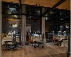 a dining room with tables and chairs and windows at Biohotel Gralhof in Weissensee